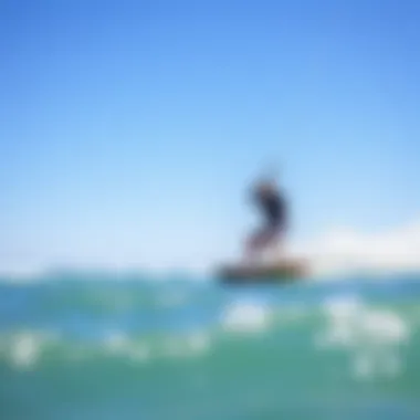 Riding the Waves: The Thrill of Kitesurfing A kitesurfer riding a wave against a backdrop of clear blue skies