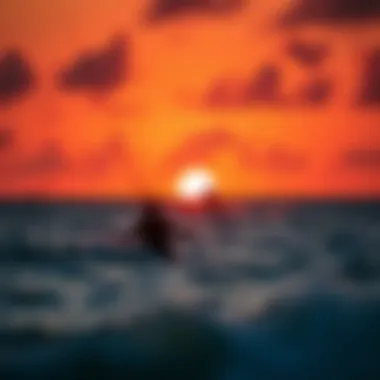 Kiteboarders riding the waves against a vibrant sunset