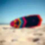 A vibrant kite surf board displayed on a sandy beach under a clear blue sky