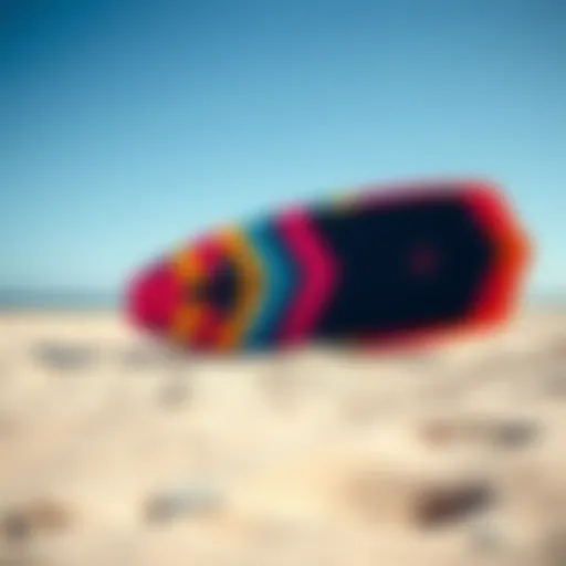 A vibrant kite surf board displayed on a sandy beach under a clear blue sky