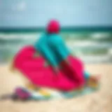 A vibrant poncho draped over a kiteboard on a beach