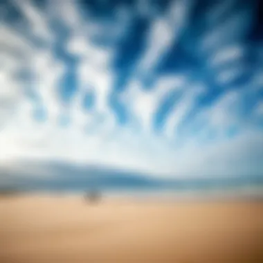 A scenic view of a beach with varying cloud patterns affecting kiteboarding conditions