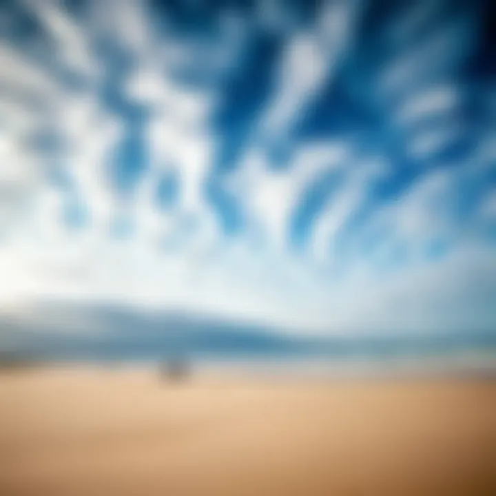 A scenic view of a beach with varying cloud patterns affecting kiteboarding conditions